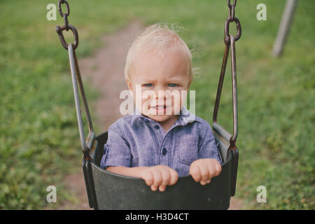 Portrait of baby boy on swing in playground Banque D'Images