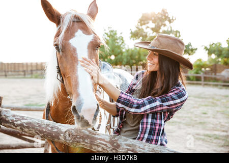 Portrait of happy young woman standing outdoors cheval avec cowgirl Banque D'Images