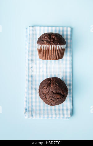 Les muffins au chocolat savoureux sur serviette à carreaux. Vue d'en haut. Banque D'Images