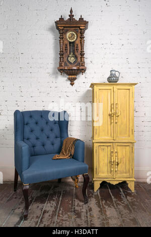 Still Life of vintage fauteuil bleu, jaune placard, horloge à pendule et orange écharpe ornée en studio Banque D'Images