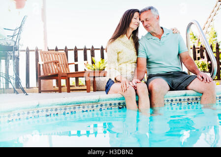 Un couple assis côte à côte sur le bord d'une piscine. Banque D'Images