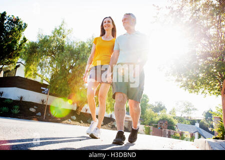 Couple portant des shorts de marcher le long d'une rue au soleil. Banque D'Images