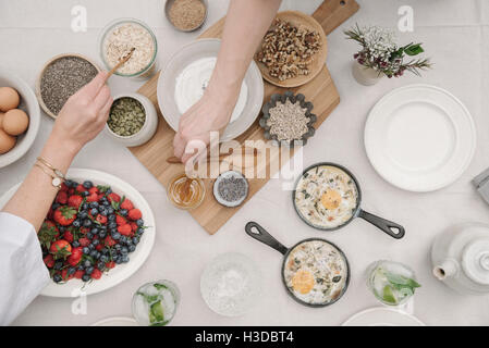 Petit-déjeuner de fruits, petits fruits et yaourts, oeufs et omelettes cuites. Deux personnes pour atteindre de la nourriture. Banque D'Images