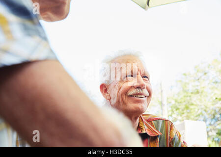 Smiling senior Homme avec moustache assis en plein air company. Banque D'Images