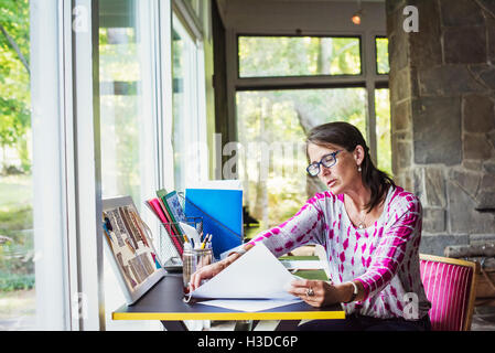 Femme assise à un bureau à domicile, et le travail. Banque D'Images