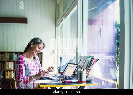 Femme assise à un bureau à domicile, et le travail. Banque D'Images