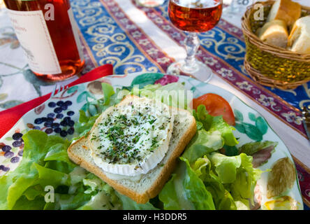 Déjeuner rustique en plein air français de fromage de chèvre sur toast de chèvre avec salade et vin rose au restaurant Au Bon Accueil, Beaune, Côte d'Or, France. Banque D'Images