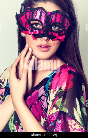 Belle jeune femme portant un masque visage touchant la main Banque D'Images