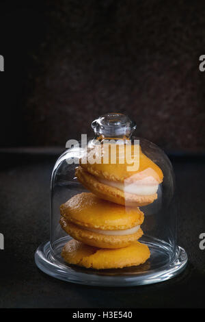 Orange citron macarons faits maison avec du chocolat blanc en cloche de verre bol texture noire. Banque D'Images