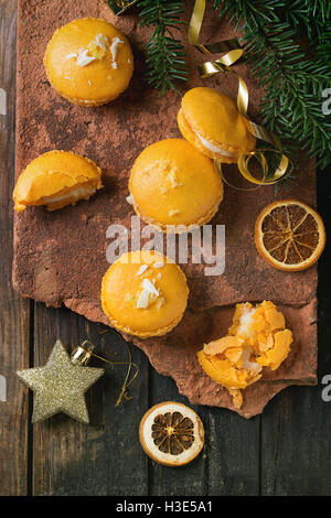 Ensemble et broken orange citron macarons fait maison avec le chocolat blanc et le sucre et le zeste d'agrumes sur l'ancien conseil d'argile plus en bois Banque D'Images