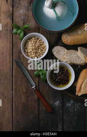 Bol Turquoise ensemble lié à la saumure de burrata fromage italien servi avec des tranches de pain, les noix de pin, le basilic et les tomates séchées dans l' Banque D'Images