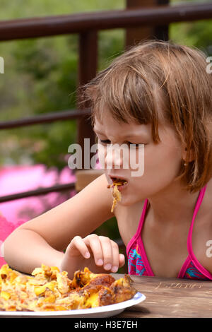 Très faim fille mange du poulet grillé Banque D'Images