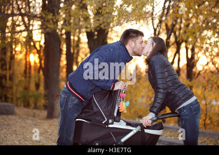 Heureux parents kiss pour une promenade près de la poussette Banque D'Images