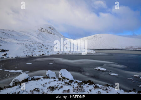 Lock Skeen partiellement congelée et les collines environnantes de la mi Craig (à gauche) et Lochcraig (derrière la tête) couverts dans la neige profonde, Gris Mar Banque D'Images