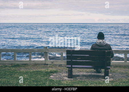 Homme assis sur banc avec vue sur mer Banque D'Images