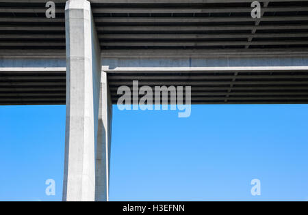 Face inférieure des grands pylônes en béton pont de l'autoroute et à angle droit contre le ciel bleu clair. Banque D'Images