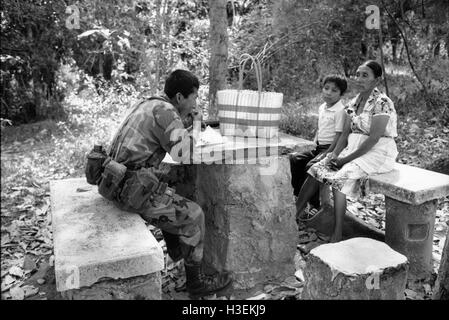 SAN SALVADOR, EL SALVADOR, FEB 1990 Une mère voit son fils, un soldat de l'armée de terre Salvadorn, manger la nourriture qu'elle lui a apporté lors d'une visite dans sa caserne. Banque D'Images