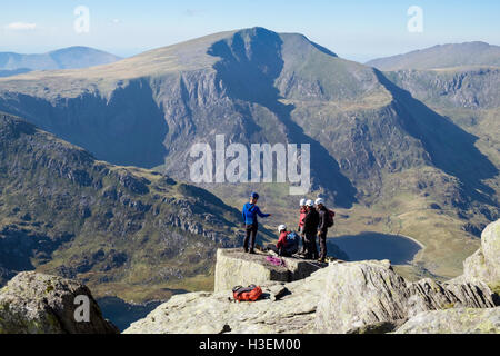 Les hommes l'apprentissage de l'escalade sur un rocher de Tryfan avec vue sur Y Garn en toile de fond dans les montagnes du Parc National de Snowdonia (Eryri). Ogwen Wales UK Banque D'Images