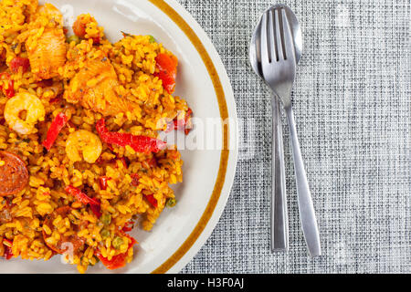 Poulet au chorizo, plaqué et king prawn paella avec une cuillère et fourchette sur un tapis de table Banque D'Images