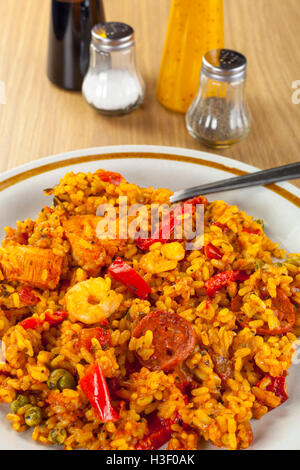 Poulet au chorizo, plaqué et paella langoustines sur une table en bois avec une sélection de condiments Banque D'Images