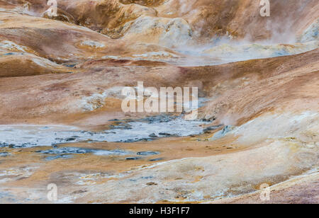 Paysage géothermique Krafla en Islande avec terre rouge, un flux d'eau chaude, la vapeur et les touristes. Banque D'Images