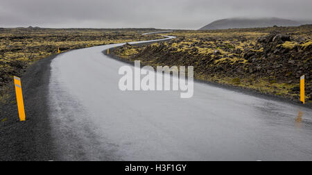 Route à travers le paysage noir vulconic sur l'Islande un jour de pluie. Banque D'Images