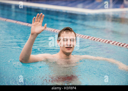 Jeune homme heureux dans la piscine gesturing thumb up Banque D'Images