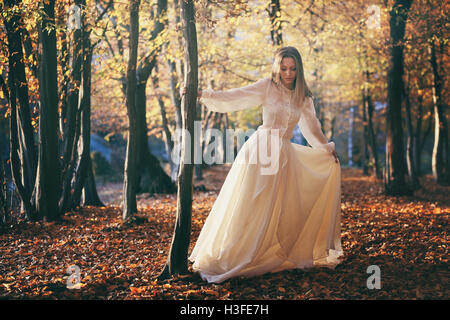 Femme avec robe victorienne dancing en automne les bois. Des couleurs de saison Banque D'Images