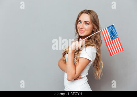 Heureux belle jeune femme debout et tenant un drapeau des États-Unis d'Amérique Banque D'Images