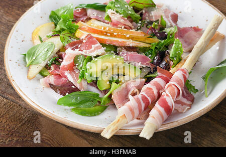 Salade fraîche à la pancetta et des bâtonnets sur une table en bois. Banque D'Images