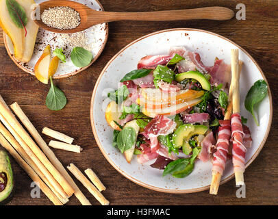 Salade fraîche à la pancetta et des bâtonnets sur une table en bois. Mise à plat Banque D'Images