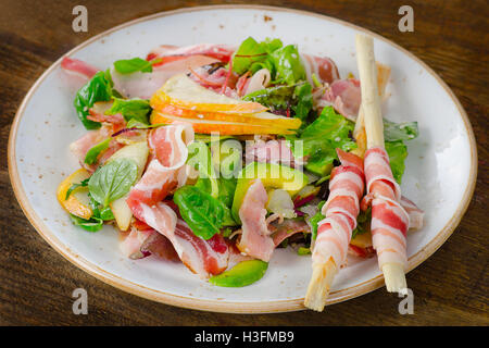 Salade fraîche à la pancetta et poire sur une table en bois. Banque D'Images