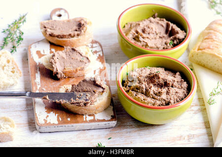 Le pâté de foie de poulet avec du pain sur une planche de bois blanc. Selective focus Banque D'Images