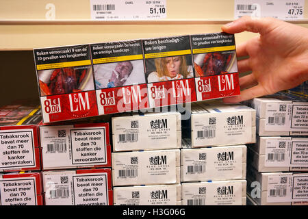 Des cigarettes dans un commerce de gros avec des photos sur les paquets de cigarettes pour illustrer les dangers du tabagisme Banque D'Images