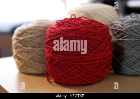 Boules de coton laine fils de soie sur table en bois rouge gris blanc et marron Banque D'Images