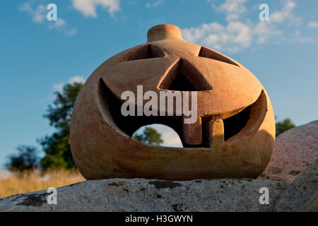 Une citrouille en terre cuite avec les yeux, le nez et la bouche et deux dents, prêt pour l'Halloween Banque D'Images
