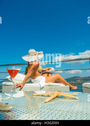 Femme avec un cocktail rafraîchissant au bord de la piscine à débordement en Grèce Banque D'Images