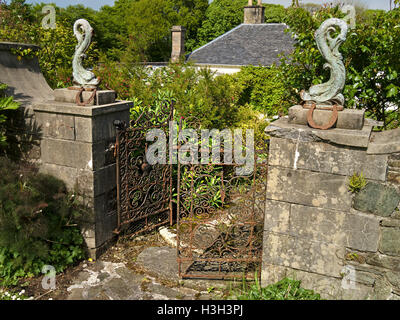 Old rusty portail porte en fer forgé ornée de poissons et de statues, un fleuron Colonsay House Gardens, à l'île de Colonsay, Ecosse, Royaume-Uni. Banque D'Images