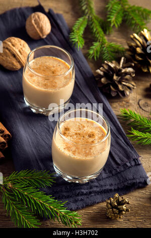 Lait de poule à la cannelle dans des verres sur fond rustique en bois avec décoration de Noël - boisson festive traditionnelle faite maison pour Chr Banque D'Images