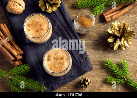 Lait de poule à la cannelle dans des verres sur fond rustique en bois avec décoration de Noël - boisson festive traditionnelle faite maison pour Chr Banque D'Images