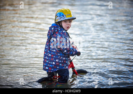 Un jeune garçon essaie de se déplacer dans l'eau d'inondation sur Abingdon Road à Oxford Banque D'Images