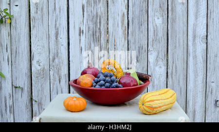 Les fruits et légumes récoltés dans la fin de l'été, dans le panier rouge, sur tan, nappe décorée de blé d'Inde Banque D'Images