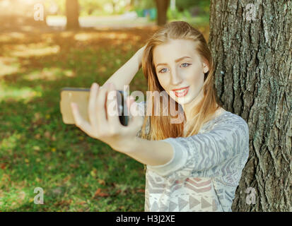 Belle jeune fille aux yeux bleus, rend l'extérieur selfies Banque D'Images