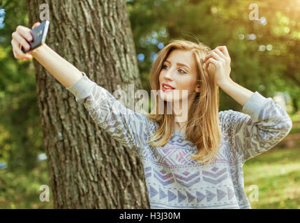 Belle jeune fille aux yeux bleus, rend l'extérieur selfies Banque D'Images