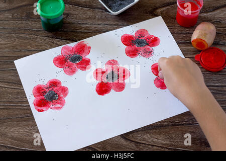 Dessin sur papier coquelicots, enfant dessine les graines de pavot. Peinture, Colle, papier et les pommes de terre sur une table en bois. Projet d'art pour enfants, une Banque D'Images