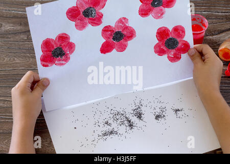 Dessin sur papier coquelicots, enfant dessine les graines de pavot. Peinture, Colle, papier et les pommes de terre sur une table en bois. Projet d'art pour enfants, une Banque D'Images