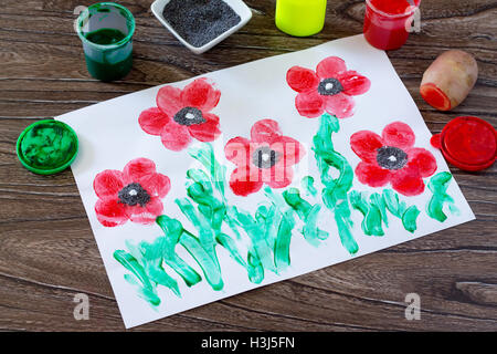 Dessin sur papier coquelicots réalisés dans la technique de pommes de terre d'empreintes digitales et les doigts. Peinture, Colle, papier et les pommes de terre sur un sol en bois Banque D'Images