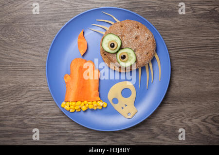 Halloween spider, bougie et crâne fait de pain et de légumes sur la plaque Banque D'Images