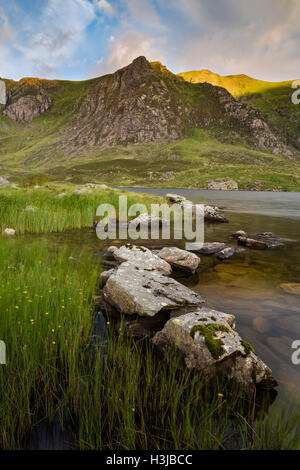 Llyn Idwal, Snowdonia, se tient sous Castell y Geifr et Y Garn, qui est baignée dans la lumière dorée du soleil. Banque D'Images