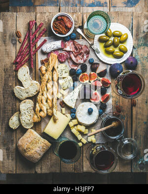 Vin et snack-set avec différents vins dans les verres, variété de viande, pain, tomates séchées, miel, olives vertes, figues, noix et f Banque D'Images